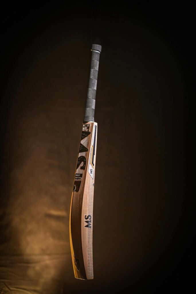 A high-quality wooden cricket bat suspended in a dark studio setting, showcasing its craftsmanship and design.