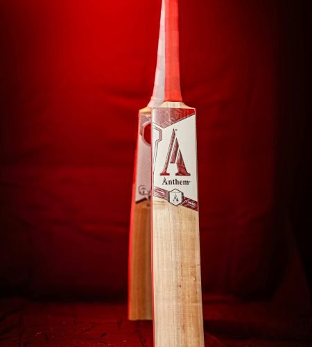 A striking image of a cricket bat illuminated by red light, showcasing sporting equipment.